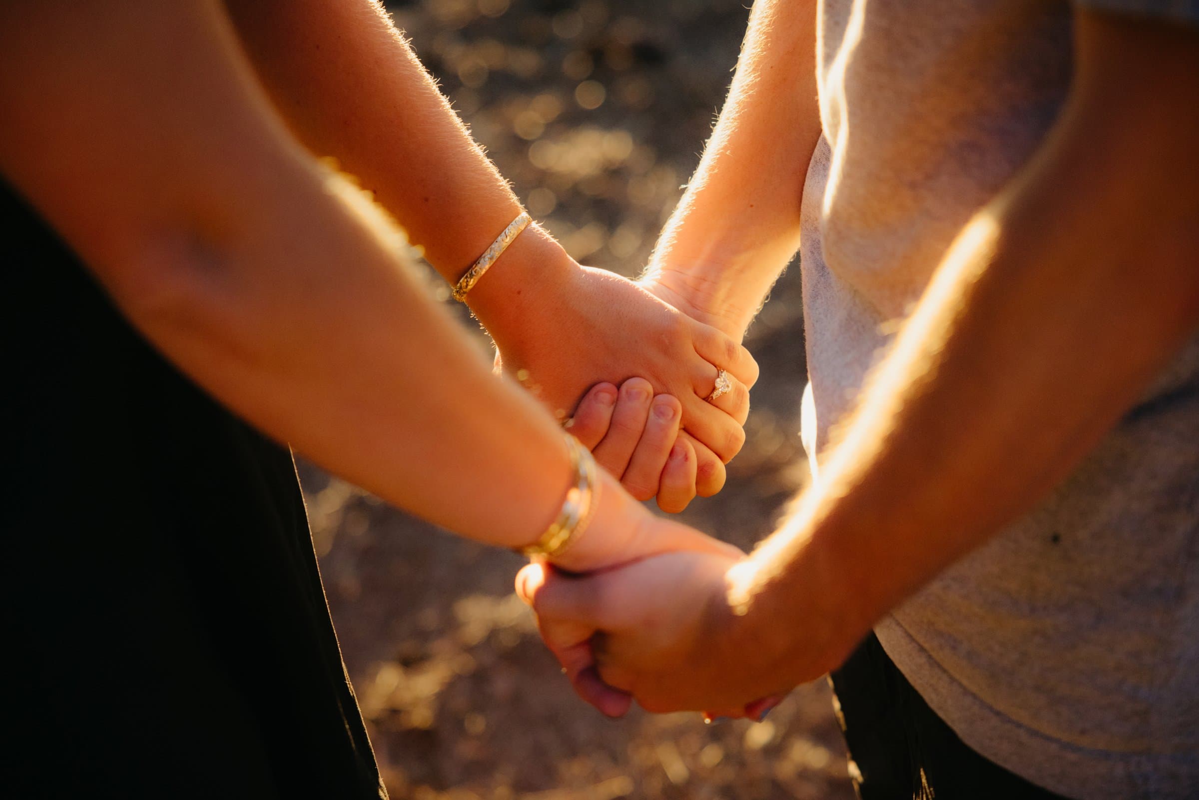 Two hands held together, an engagement ring catching the light