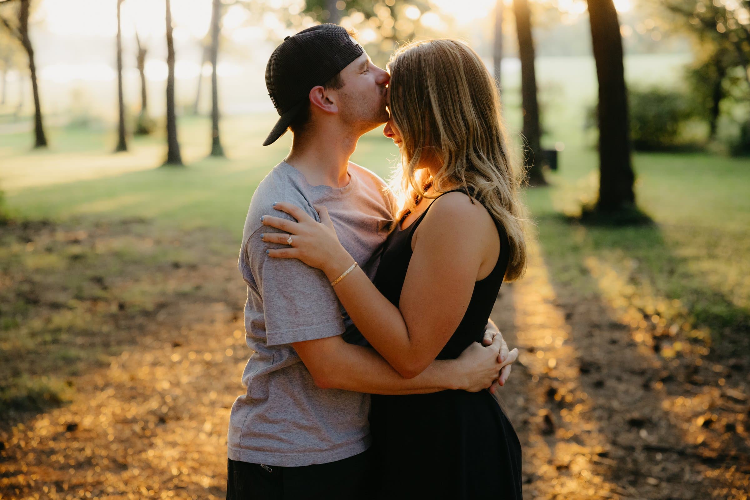A kiss on the forehead in an open field at sunset