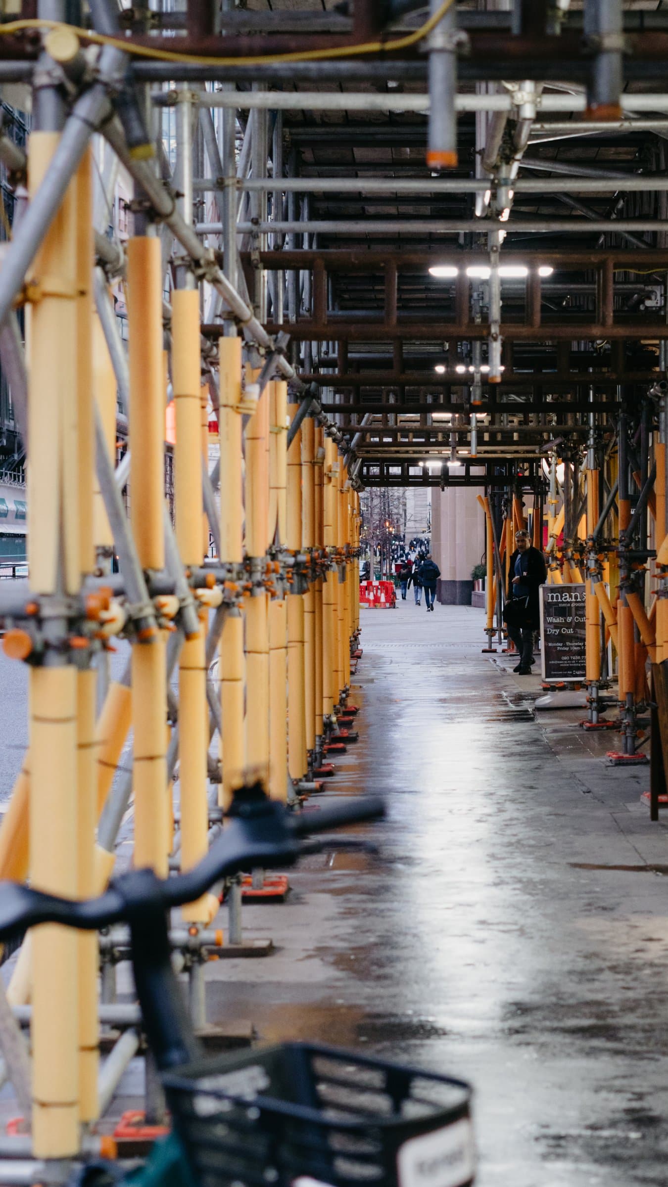 A yellow scaffolding corridor on a wet London street
